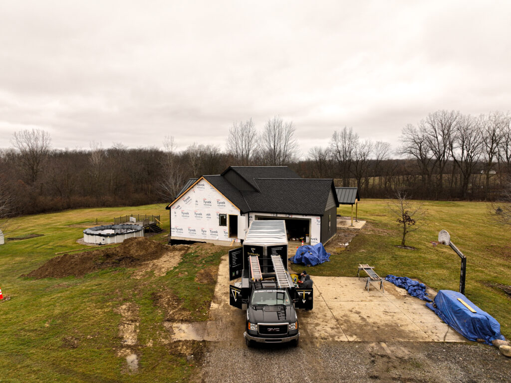 House under construction with a dark shingle roof and Tri-County work truck in the driveway